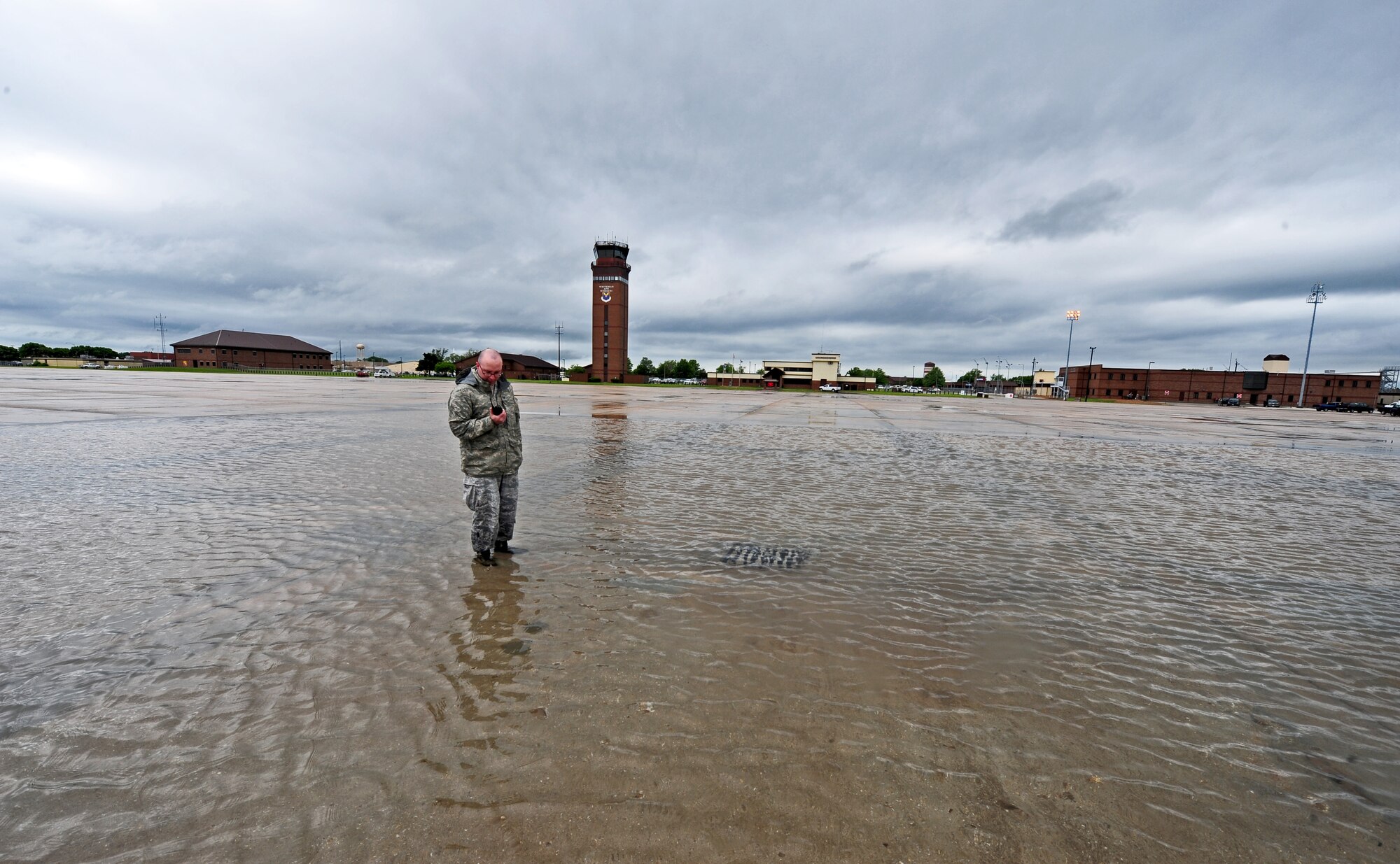 Staff Sgt. Timothy Cole, 509th Operations Support Squadron airfield management operations supervisor, calls in the status of rainwater on the flightline during a daily safety inspection at Whiteman Air Force Base, Mo., May 31, 2013. During heavy rainstorms, airfield managers close off areas that have too much water buildup to prevent pilots and vehicle operators from sliding and losing control. (U.S. Air Force photo by Staff Sgt. Nick Wilson/Released)