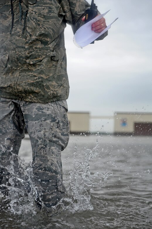 Staff Sgt. Timothy Cole, 509th Operations Support Squadron airfield management operations supervisor, treads through water that is almost knee-high to conduct a rainwater assessment at Whiteman Air Force Base, Mo., May 31, 2013. Airfield Management's responsibilities include providing support to various aircraft operations and enabling continuation of operations after emergency situations. (U.S. Air Force photo by Staff Sgt. Nick Wilson/Released)