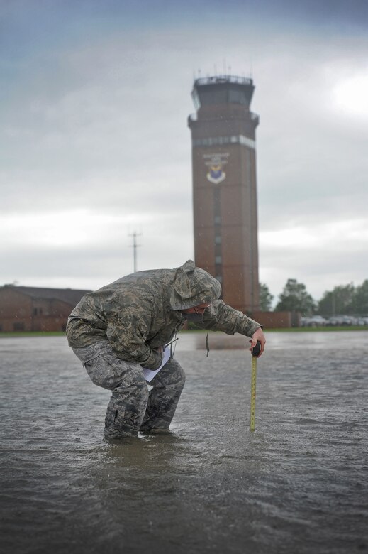 Staff Sgt. Timothy Cole, 509th Operations Support Squadron airfield management operations supervisor, measures the depth of rainwater on the flightline during a rainstorm at Whiteman Air Force Base, Mo., May 31, 2013. One of Coles’ responsibilities is ensuring aircraft are able to safely taxi on the flightline to support contingency taskings and Air Force Global Strike Command operations. (U.S. Air Force photo by Staff Sgt. Nick Wilson/Released)