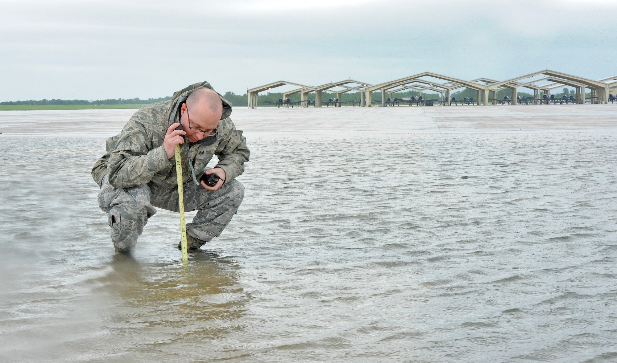 Staff Sgt. Timothy Cole, 509th Operations Support Squadron airfield management operations supervisor, gathers a rainwater assessment during a rainstorm at Whiteman Air Force Base, Mo., May 31, 2013. Airfield managers must ensure aircraft movement areas are free from running water and other obstacles that could pose a threat to aircraft operations. (U.S. Air Force photo by Staff Sgt. Nick Wilson/Released)