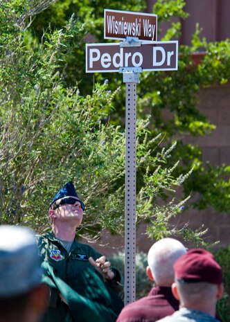 Staff Sgt. Christopher Cholet, 66th Rescue Squadron flight engineer, unveils a street sign during a street renaming ceremony June 10, 2013, at Nellis Air Force Base, Nev. Family members of the PEDRO 66 crew were present during the ceremony. (U.S Air Force photo by Airman 1st Class Jason Couillard)