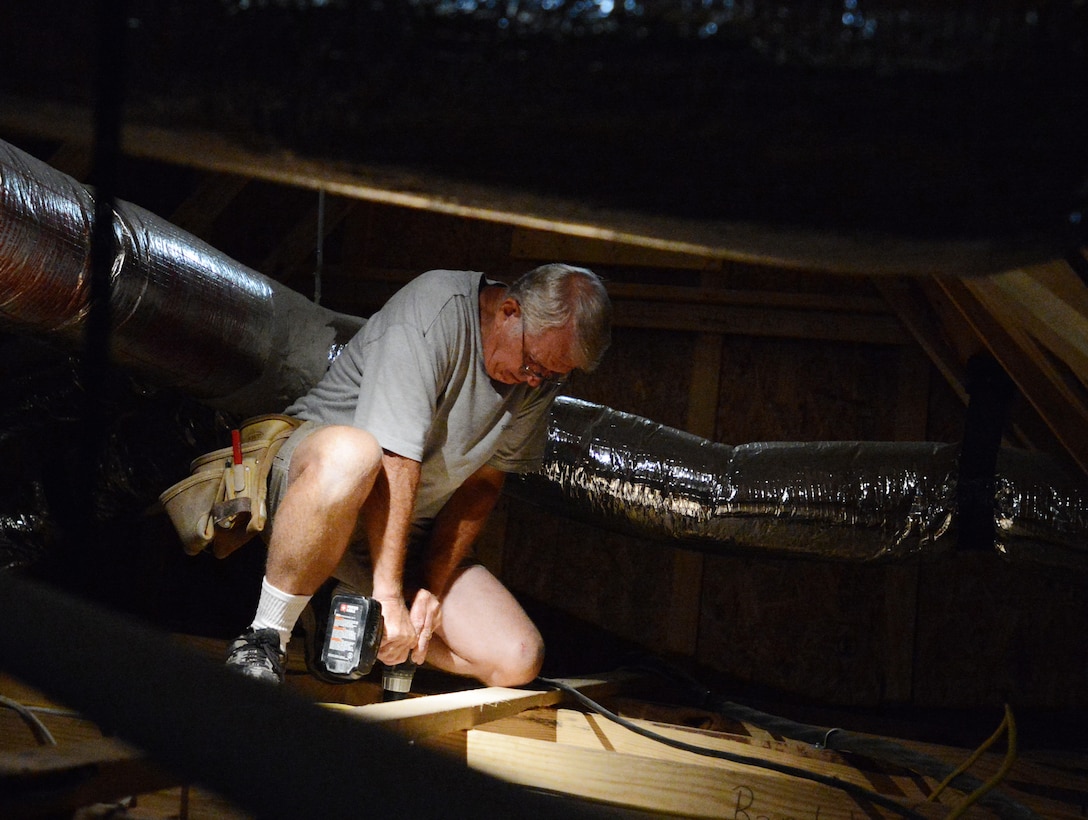 Robert Brown, Habitat for Humanity construction director, drills a hole in the attic of a Habitat for Humanity home in Sumter, S.C., May 29, 2013. Hundreds of Team Shaw members volunteer with habitat to build and repair homes in the local area. (U.S. Air Force photo by Senior Airman Tabatha Zarrella/Released)