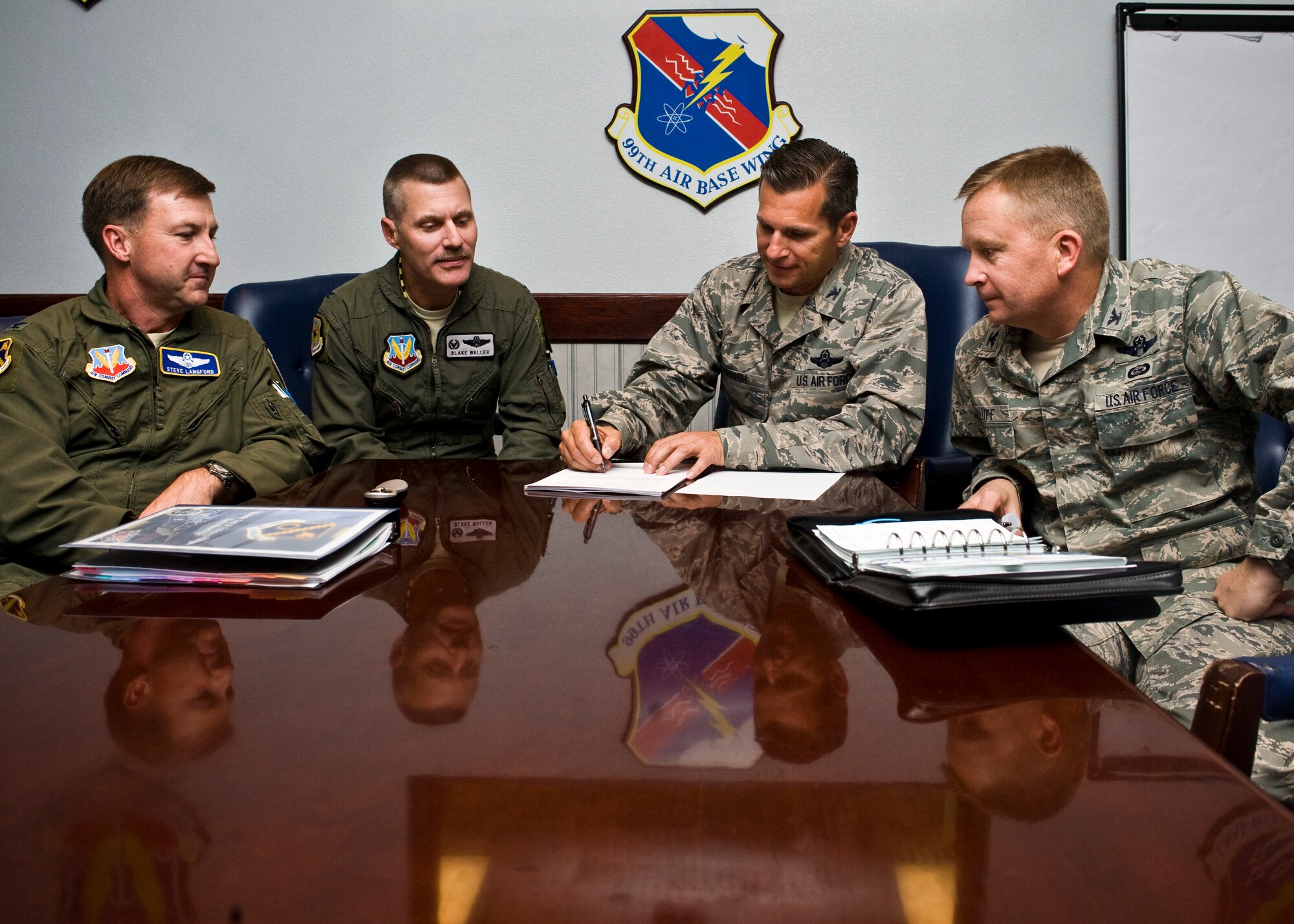 Col. Steve Langford, Nevada Test and Training Range commander, Col. Stephen Waller, 57th Wing vice commander, and Col. Jim Cluff, 432nd Wing commander, watch as Col. Barry Cornish, 99th Air Base Wing commander, signs the community action plan June 6, 2013, at Nellis Air Force Base, Nev. The CAP priorities were selected based upon their impact on mission execution and foundation for long term sustainment. The three priorities are culture of respect, physical resilience, and financial wellness. The CAP's purpose identifies individual, family, and community issues while serving as a guide for Nellis AFB, Creech AFB, the NTTR, the Community Action Information Board and Integrated Delivery System teams. (U.S. Air Force Photo by Airman 1st Class Jason Couillard)