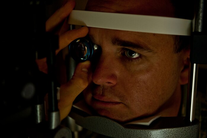 U.S. Air Force Master Sgt. David Sims, 57th Aircraft Maintenance Squadron first sergeant, has his eyes checked by Capt. (Dr.) William Catt, 99th Aerospace Medicine chief of aerospace optometry, June 7, 2013, at Nellis Air Force Base, Nev. Catt uses a magnifier, which intensifies the light into the eye and aids the doctor as he looks for diseases in the eye. (U.S. Air Force photo by Senior Airman Daniel Hughes)