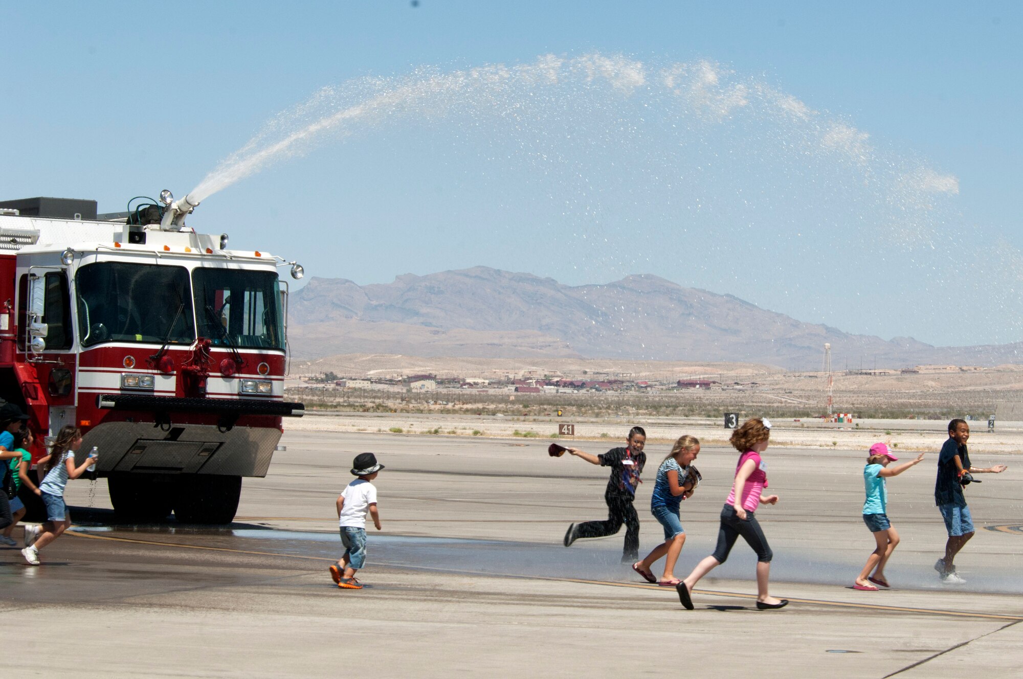Airmen From the 99th Civil Engineer Squadron Fire Department helped children from the Candlelighters Childhood Cancer Foundation of Nevada cool off by spraying water in the air for them to play in June 8, 2013, at Nellis Air Force Base, Nev. The 99th CES Fire Department provided a fire truck for a base tour hosted by the 64th Aggressor Squadron for the CCCFN. (U.S. Air Force Photo by Staff Sgt. Gregory Brook)