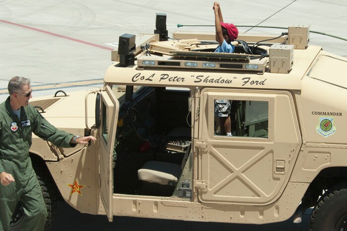 Col. Peter Ford, 57th Adversary Tactics Group commander, shows Marcus Cartin, a childhood cancer survivor, a Humvee June 8, 2013, at Nellis Air Force Base, Nev.  Airmen from the 64th AGRS with help from the 65th AGRS, the 547th Intelligence Squadron, the United States Air Force Air Demonstration Squadron Thunderbirds and the 99th Civil engineer squadron worked with the Candlelighters Childhood Cancer Foundation of Nevada to give the children a base tour and show them static displays of military equipment. (U.S. Air Force Photo by Staff Sgt. Gregory Brook)