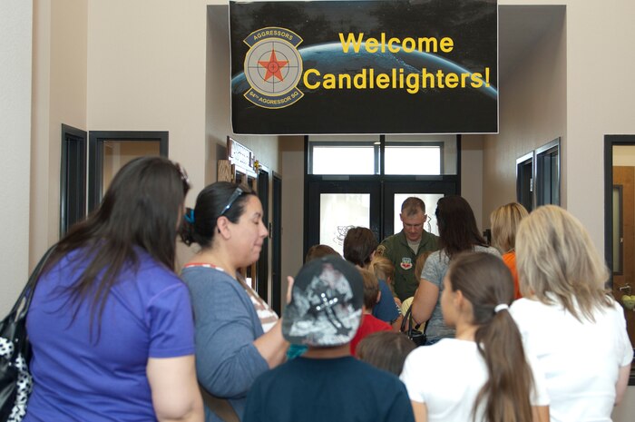 Lt. Col. Michael Shepherd, 64th Aggressor Squadron assistant director of operations for academics, greets families from the Candlelighters Childhood Cancer Foundation of Nevada June 8, 2013, at Nellis Air Force Base, Nev. Upon arrival to the squadron, children and parents were given name badges and keepsakes from the 64th AGRS to commemorate their visit. (U.S. Air Force Photo by Staff Sgt. Gregory Brook)
