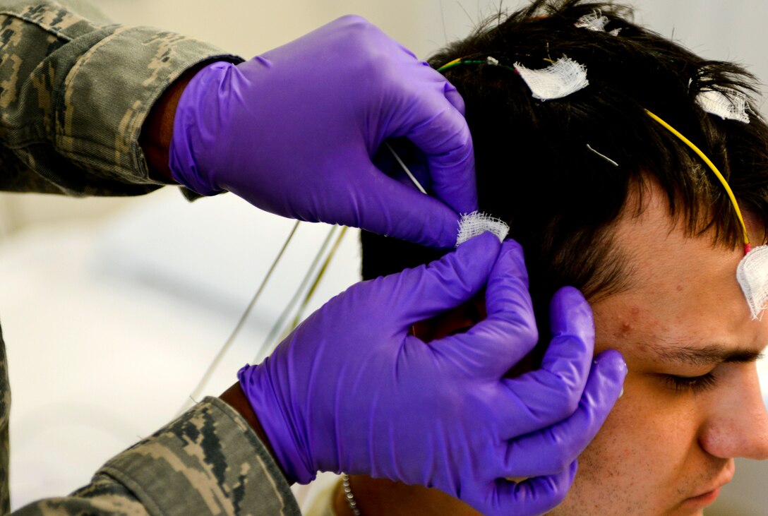 U.S. Air Force Tech. Sgt. Valarie Platt, 633rd Medical Operations Squadron Neurology Clinic noncommissioned officer in charge, places an electrode on Airman 1st Class Christopher Howell, 633rd MDOS medical technician, prior to an electroencephalography (EEG) study at U.S. Air Force Hospital Langley at Langley Air Force Base, Va., May 4, 2013. The referral-based clinic sees between 120 and 140 patients monthly, focusing on individual, personalized care. (U.S. Air Force photo by Airman 1st Class R. Alex Durbin/Released)