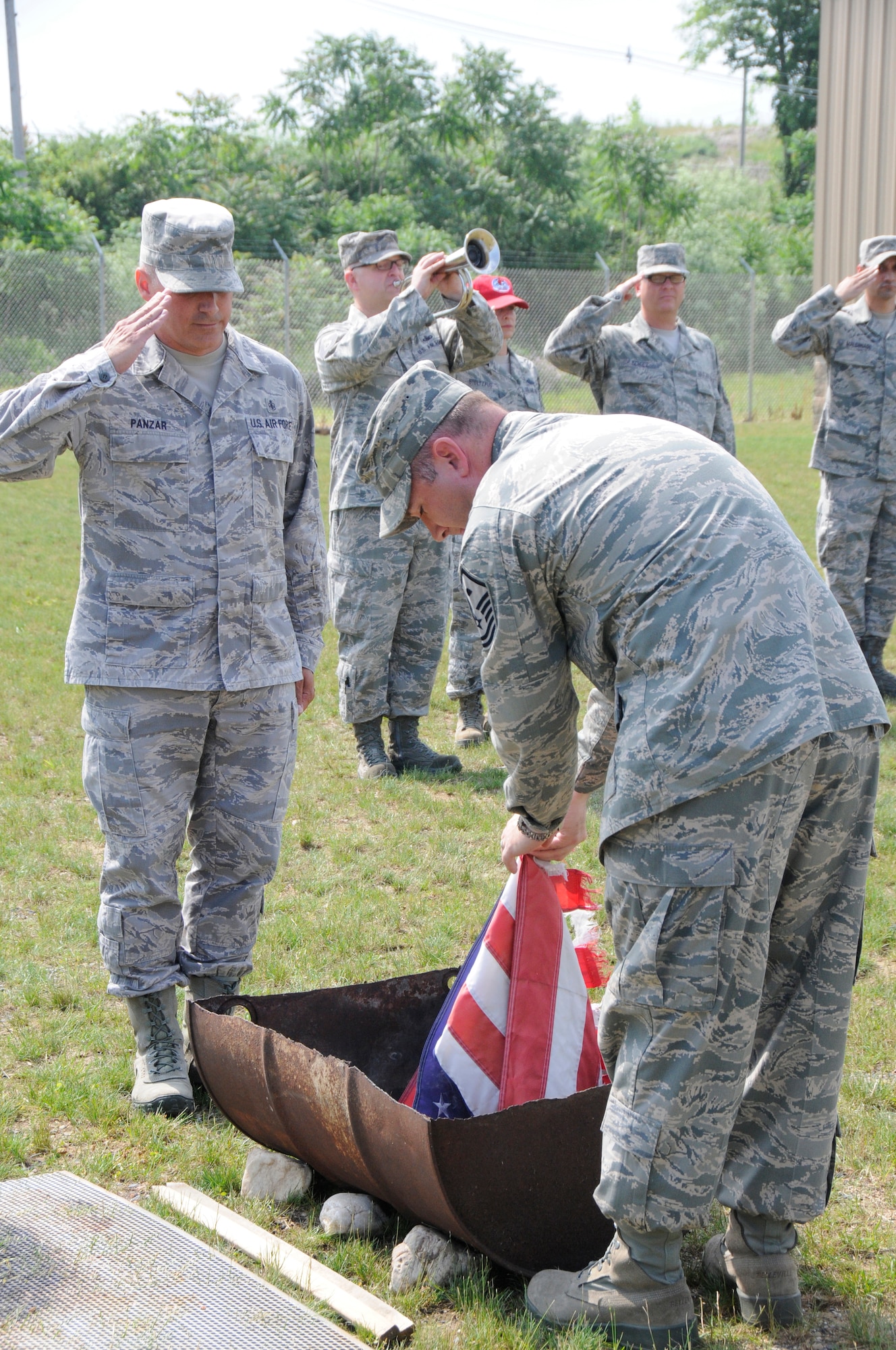 Members of the 193rd Special Operations Wing pay tribute to a U.S. flag as it is properly retired by Master Sgts. Richard Panzar (left) and Jeremy Fisher during a ceremony on base June 9. Spearheaded by the 193rd SOW First Sergeants Council, the flag retirement ceremony reinforced to military members and guests the protocol for disposing of flags that are tattered, worn, faded or otherwise unserviceable. (U.S. Air National Guard photo by Staff Sgt. Susan Penning/Released)