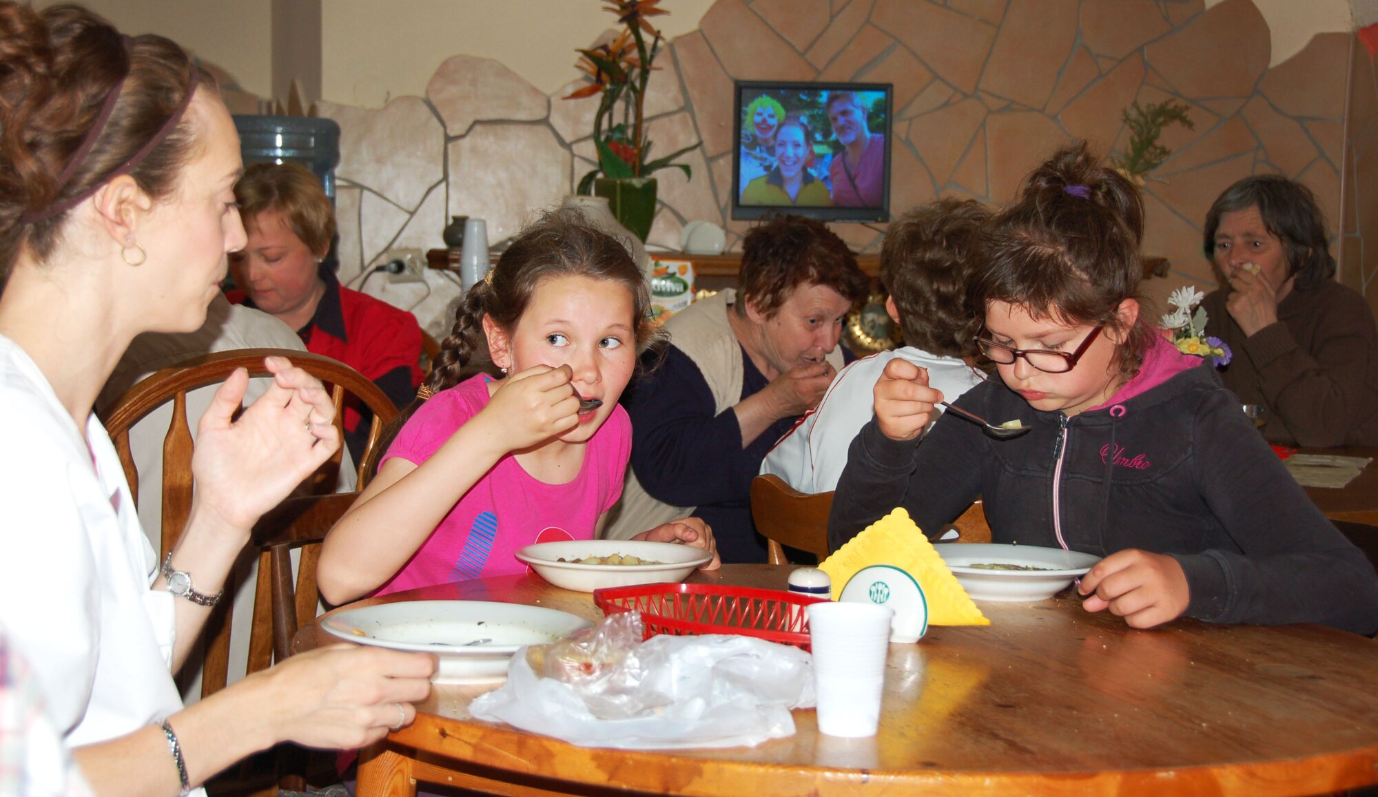 LWOWEK SLASKI, Poland – Dr. Tricia Bogaard, an optometrist from Spangdahlem Air Base, Germany, shares a table with two of the young girls who come daily to the Elim Center for school lunch, which is provided at no cost to the school and students and has been an ongoing program for 19 years and feeds up to 50 children a week. Founded in 1992, the Elim Christian Center has served the people of Lwowek Slaski, Poland by feeding, clothing, educating and ministering to people in 30 surrounding villages. (U.S. Air Force courtesy photo/Released)
