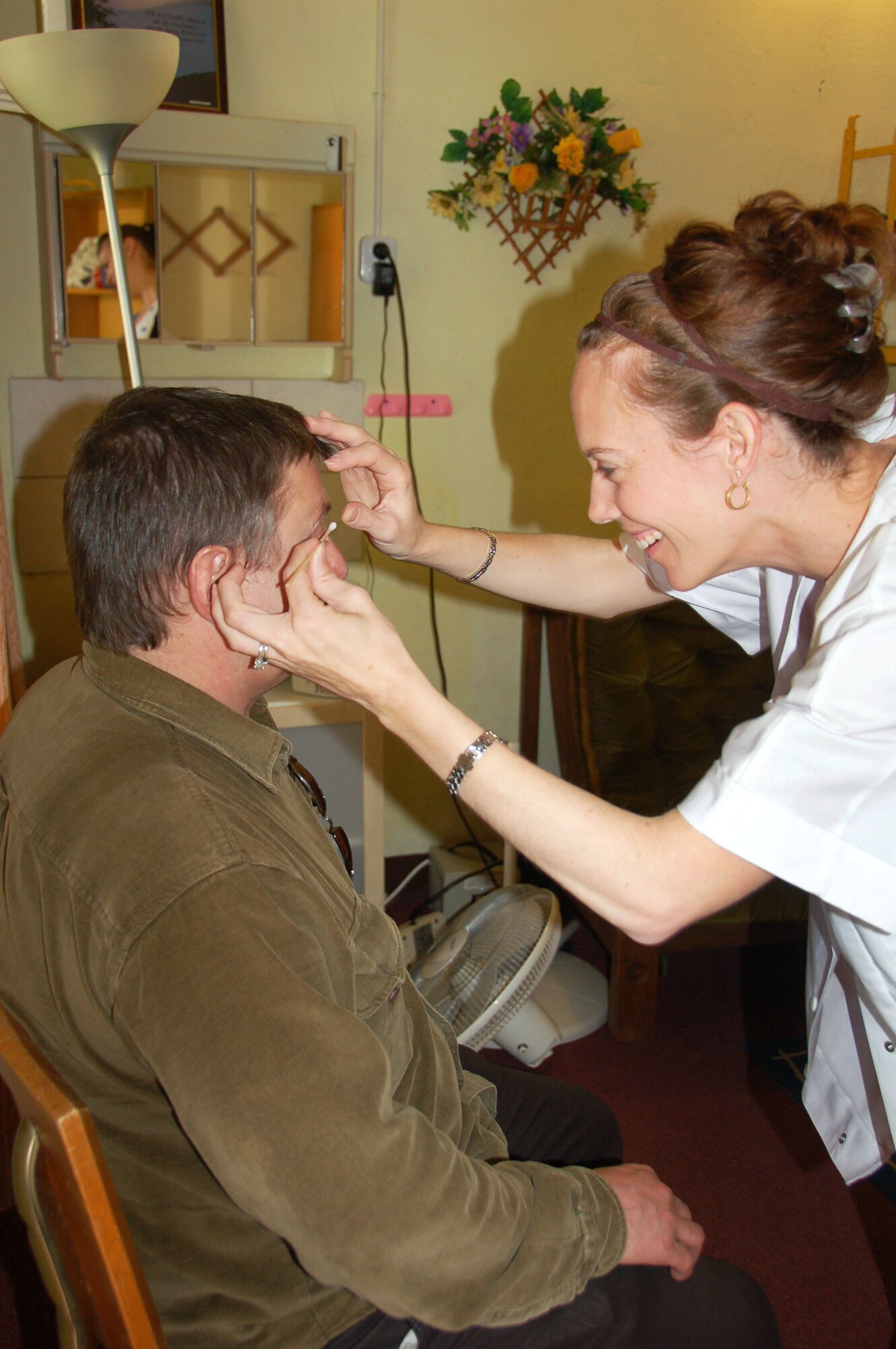 LWOWEK SLASKI, Poland – Dr. Tricia Bogaard, an optometrist from Spangdahlem Air Base, examines a patient, preparing to look under the eyelid. The Hearts for Elim medical missions trip team also included a medical provider and other women with medical experience that helped run a temporary clinic and pharmacy full of donated items for those in need of free medical care. 22 women total from Spangdahlem, Ramstein and Sweinfurt, collectively known as "Hearts for Elim," went to Poland with a mission to provide medical service as well as to donate their time and effort to serve the Elim Christian Center and the people of the local community. (U.S. Air Force courtesy photo/Released)