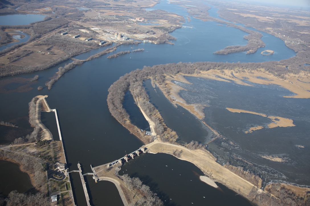 Looking upstream of Lock and Dam 3, the bend leading into the navigation structure is clearly visible. Part of a recent construction project to was extended upstream guidewall. Along withother related channel and streambank work greatly improves channel characteristics for approaching navigation tows.  A ribbon cutting ceremony is held at Lock and Dam 3 in Welch, Minn., May 31, 2013. The event signified the completion of the nearly $70 million dollar project that significantly improves the navigational safety of boats entering the lock.