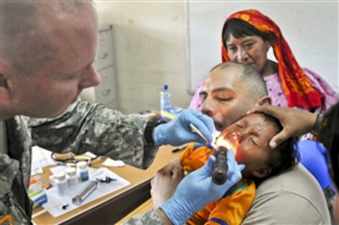 U.S. Army Maj. Matthew Brice, left, examines a child while U.S. Army Spc. Souheil Sarrouh provides comfort during medical training as part of Beyond the Horizon-Panama 2013 in Catina, Panama, May 29, 2013. The exercise, sponsored by U.S. Southern Command and led by U.S. Army South, deploys U.S. military engineers and medical personnel for training while providing humanitarian and civic assistance. Brice, a physician, and Sarrouh, a combat medic, are assigned to the 256th Combat Support Hospital.