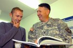 Besmir Sylejmani (left) and Col. Bruce Pearre (right) the senior logistics officer for Multi-National Task Force - East, in an office at Camp Bondsteel in Kosovo where they recently met and went through Sylejmani's senior year book while getting reacquainted. Sylejmani, who was a foreign exchange student when he met the Pearre family, left New Bloomfield, Mo., shortly after graduation. He had never seen the yearbook.