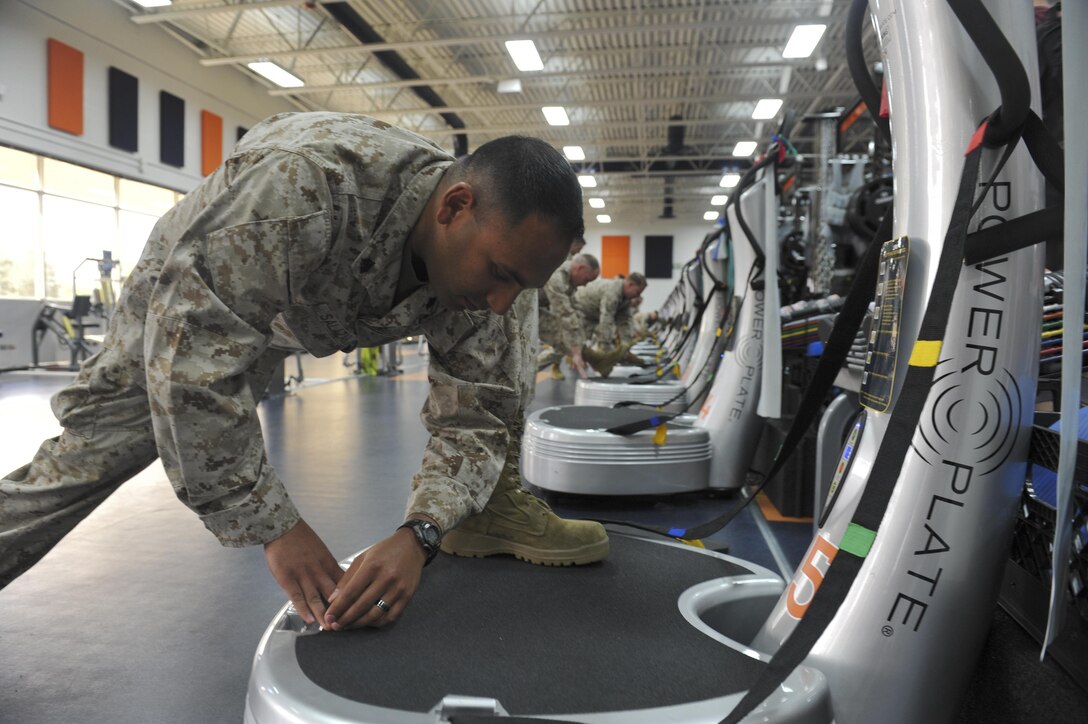 Sgt. Matthew Salazar, Company B, Intelligence Support Battalion, Force Headquarters Group, stretches on a Power Plate machine during a tour June 7, 2013, at the Denver Broncos training facility in Englewood, Colo. The Broncos strength and training coaches shared fitness tips during the tour to 12 Buckley Air Force Base, Colo. Marines. 