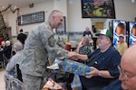 Senior Master Sgt. Paul Tangen, first sergeant for the 119th Wing, gives a Christmas gift to Roger Severson, a veteran of the Vietnam War, Dec. 10 at the North Dakota Veteran's Nursing Home in Lisbon, N.D. The gifts are given to veterans at the nursing home by the North Dakota Air and Army National Guard annually.