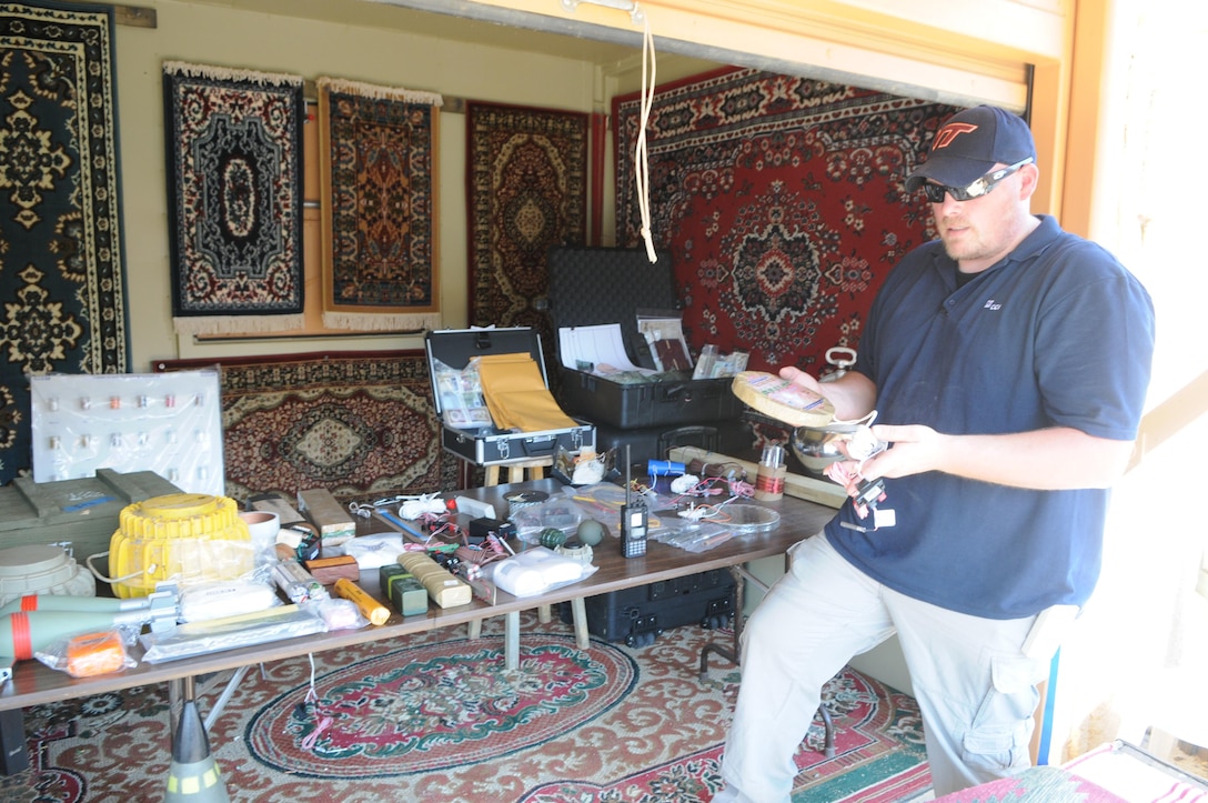 At Quantico’s Urban Training Center on May 30, 2013, Randy Powell, tactical training support specialist for the Training Support Center, shows an array of imitation improvised explosive devices the TSC has available to bring realism to training. All are based on devices that have been found in combat zones, including the rigged wire tin he holds here. 