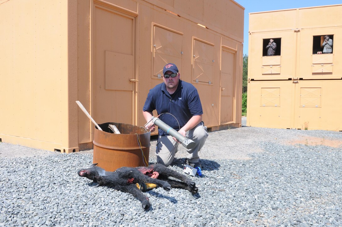 While demonstrating his ability to imitate improvised explosive devices at Quantico’s Urban Training Center on May 30, 2013, tactical training support specialist Randy Powell shows the fake mortar round that just threw up a cloud of talcum powder next to an imitation IED buried in a fake dead goat. An Explotrain OMG unit hidden across the street had produced the accompanying “boom,” while a Badger AK-47 simulator seemed to bring to life the shooter dummies in nearby windows. Powell operates all the devices by remote control. 