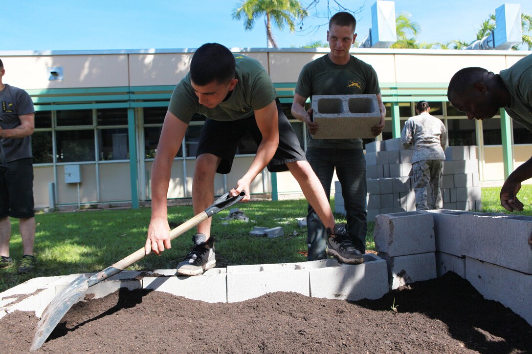 Lance Cpl. Isaac Hernandez, rifleman, 1st Platoon, Lima Company, 3rd Battalion, 3rd Marine Regiment, Marine Rotational Force - Darwin, spreads soil around the vegetable patch at the school, here, May 30. Marines with Marine Rotational Force - Darwin helped students with the foundation build a vegetable garden funded by the Consulate General of the United States, Melbourne. MRF-D Marines volunteer at the school every Thursday to help with projects like this and provide mentorship.