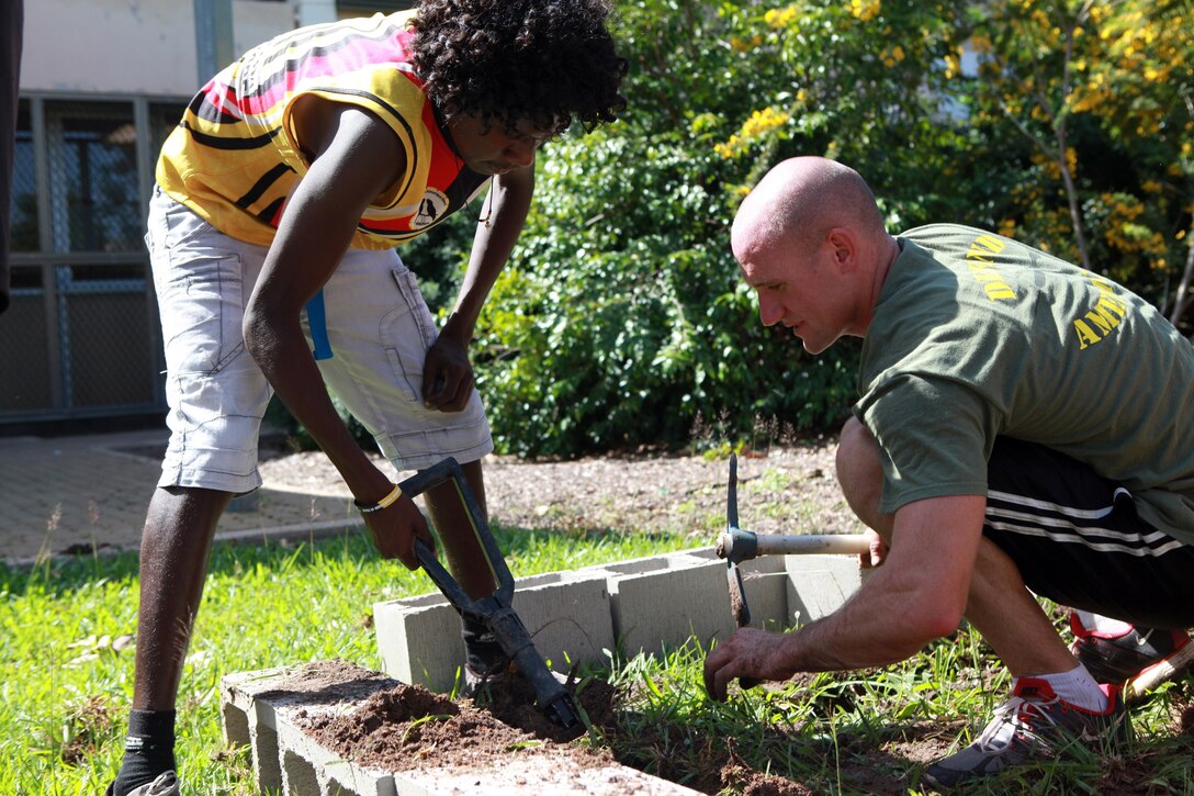 Lance Cpl. Daniel Healy, mortar man, Weapons Platoon, Lima Company, 3rd Battalion, 3rd Marine Regiment, Marine Rotational Force - Darwin, helps Michael Lindsay, a Casuarina Senior College student and member of the Clontarf Foundation, dig up dirt at the gardening site at the school, here, May 30. Marines with Marine Rotational Force - Darwin helped students with the foundation build a vegetable garden funded by the Consulate General of the United States, Melbourne. MRF-D Marines volunteer at the school every Thursday to help with projects like this and provide mentorship.