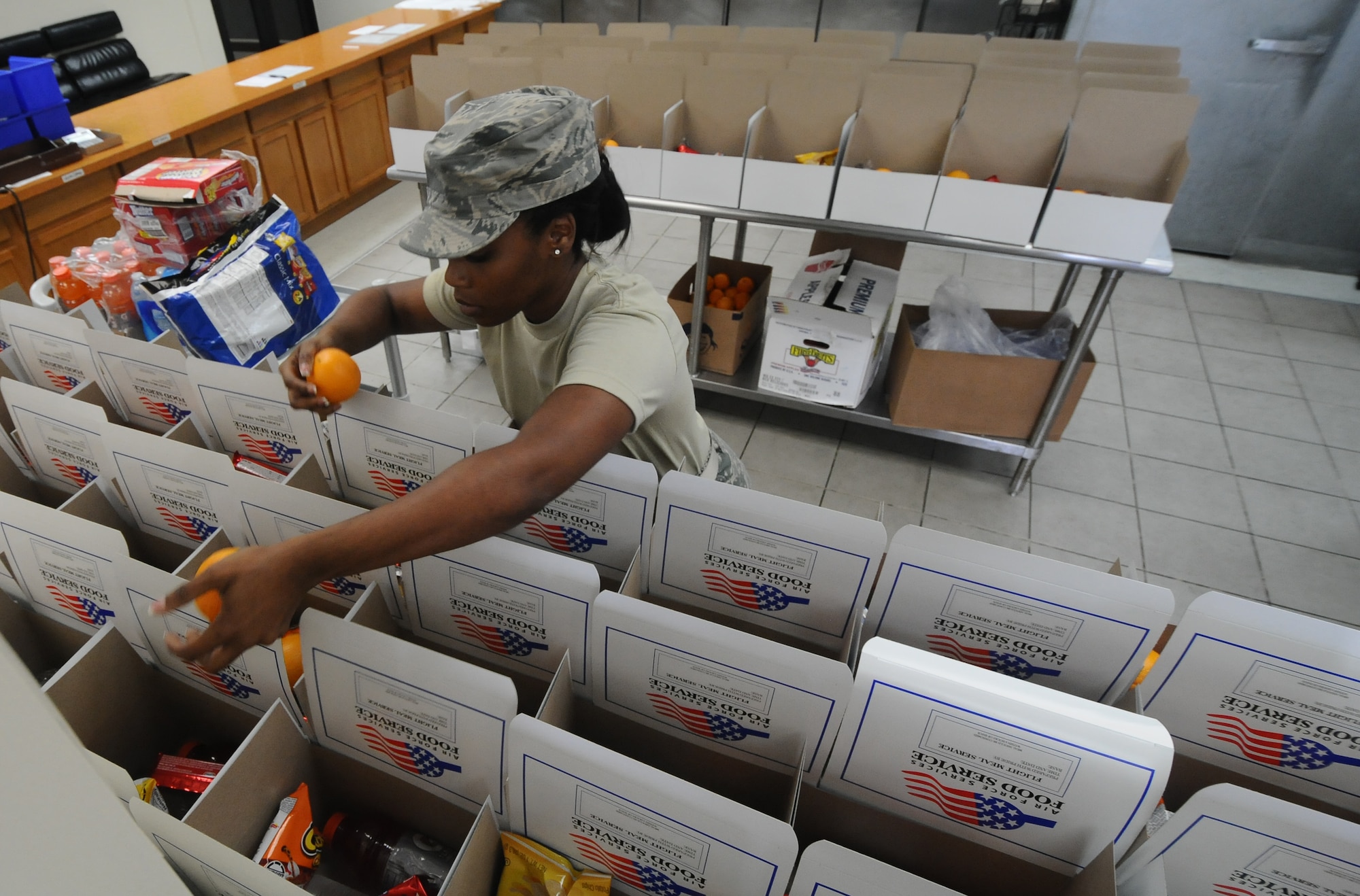 Senior Airman Angel Lewis, 36th Force Support Squadron services journeyman deployed from the Georgia Air National Guard, prepares boxed lunches by distributing oranges June 10, 2013, on Andersen Air Force Base, Guam. The 36th FSS Skyline Flight Kitchen team prepares approximately 700 boxed lunches and 1,000 hot meals per week. (U.S. Air Force photo by Airman 1st Class Emily A. Bradley/Released) 366-8136/5125