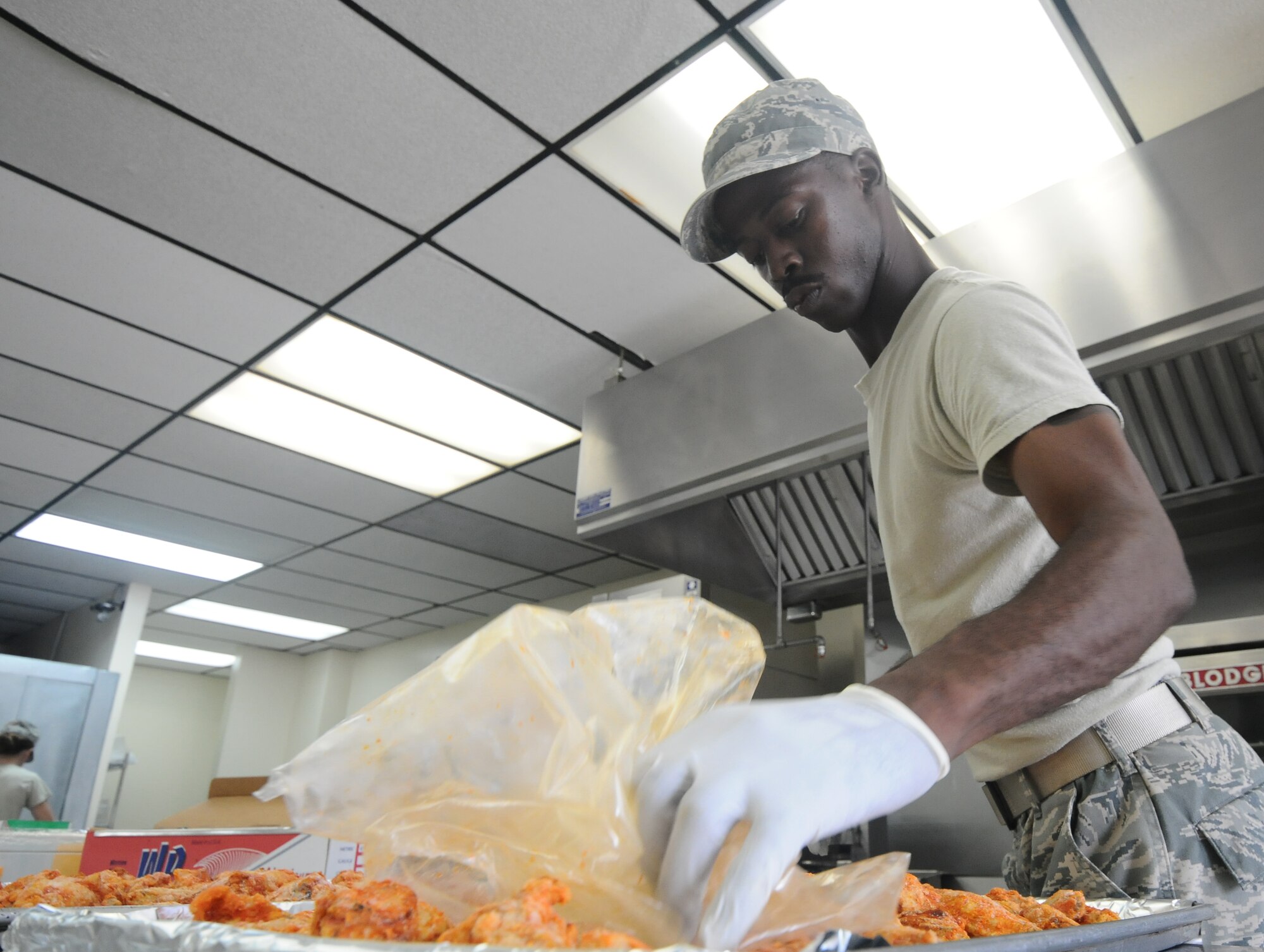 Staff Sgt. Wayne Collins, 36th Force Support Squadron food service supervisor, spreads chicken out evenly on a baking tray June 12, 2013, on Andersen Air Force Base, Guam. The Skyline Flight Kitchen prepares approximately 700 boxed lunches and 1,000 hot meals per week. (U.S. Air Force photo by Airman 1st Class Emily A. Bradley/Released)