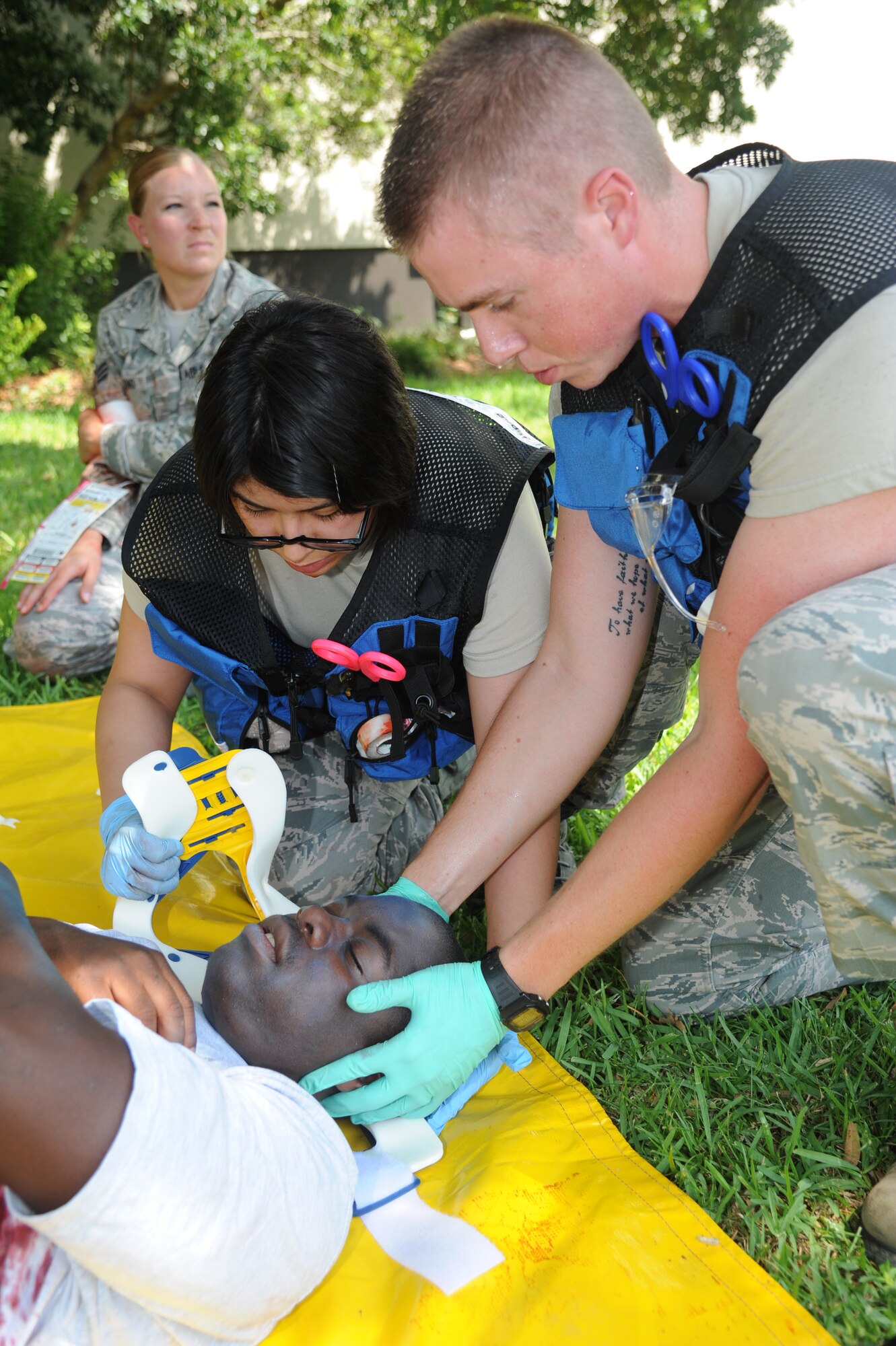 Airmen 1st Class Claudia Godinez and  Jason Parker, 81st Aerospace Medicine Squadron, apply a neck brace on Airman Cardale Keller,334th Training Squadron, who portrayed a victim during Keesler's active shooter exercise, June 12, 2013, at Garrard Hall, Keesler Air Force Base, Miss.  During the two-day exercise, an Air Force couple simulated opening fire, killing three people and injuring 41.  The exercise tested the base's ability to respond to and recover from a mass casualty event.  (U.S. Air Force photo by Kemberly Groue)