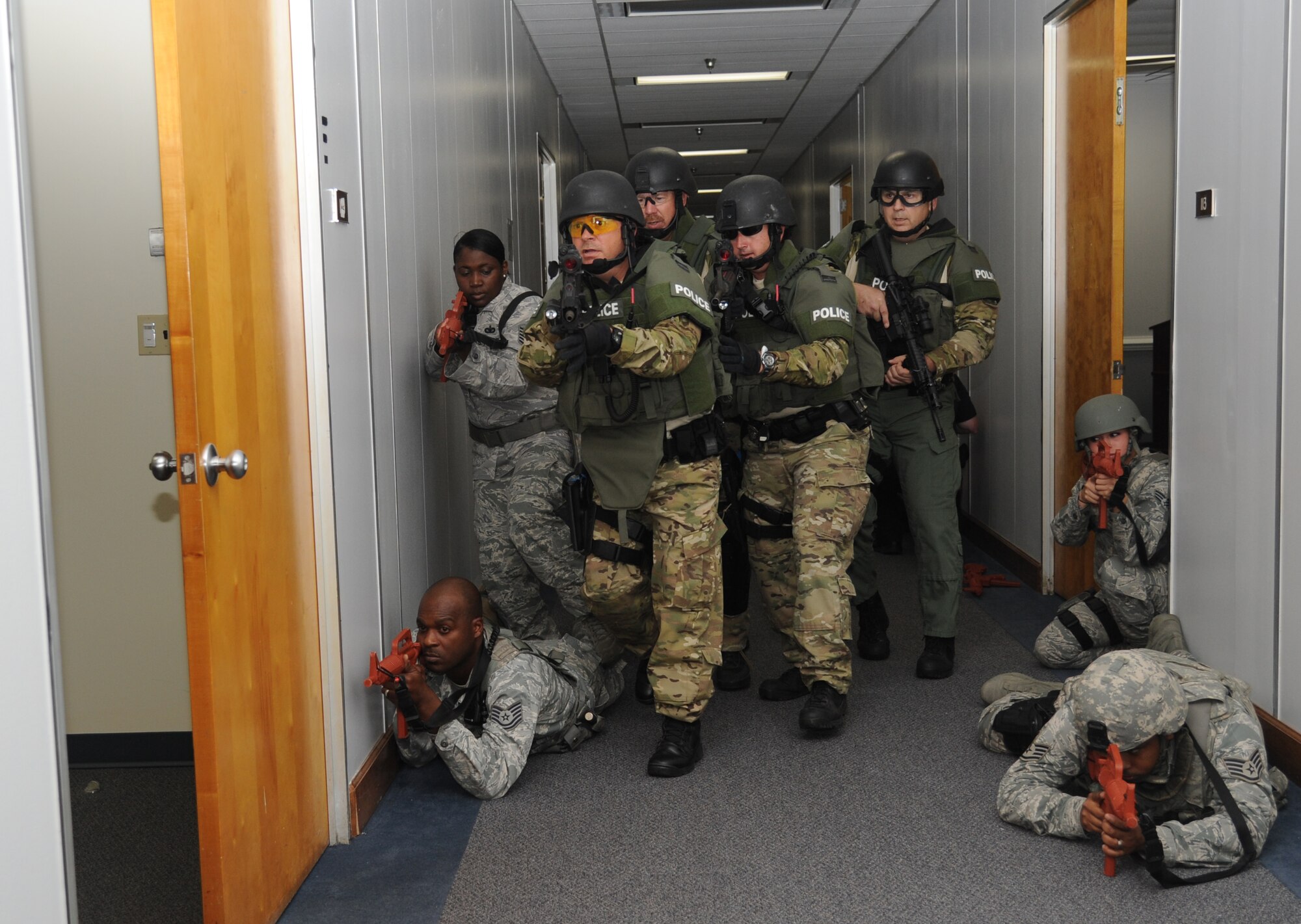 Members of the 81st Security Squadron, stands guard as Biloxi Police Department's special response team prepares to engage a portrayed gunman in a room where he is holding hostages during Keesler's active shooter exercise, June 12, 2013, at Garrard Hall, Keesler Air Force Base, Miss.  During the two-day exercise, an Air Force couple simulated opening fire, killing three people and injuring 41.  The exercise tested the base's ability to respond to and recover from a mass casualty event.  (U.S. Air Force photo by Kemberly Groue)