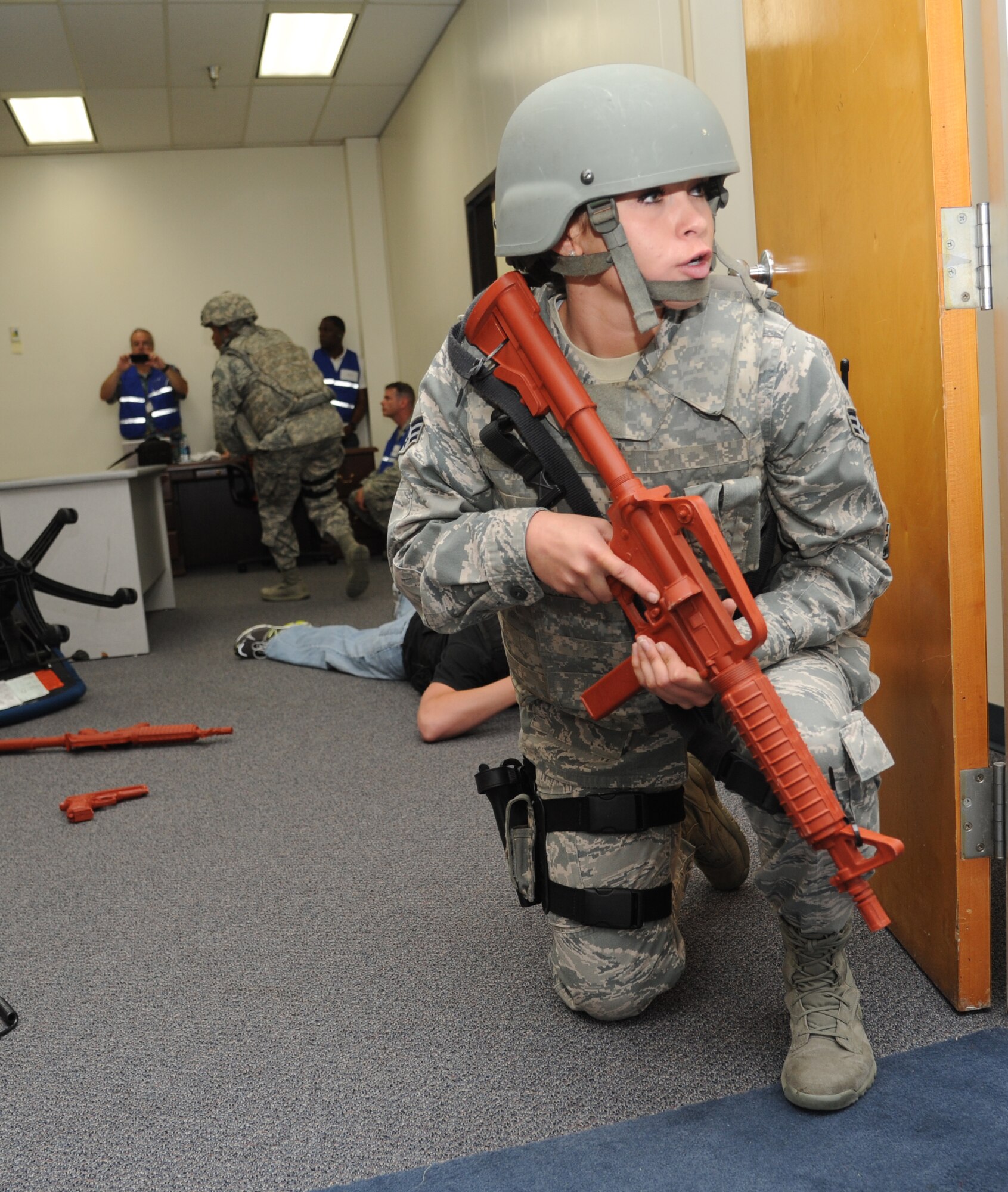 Senior Airman Brittany Beltran, 81st Security Forces Squadron, keeps a look out in the hallway as a portrayed gunman is apprehended by other 81st SFS members during Keesler's active shooter exercise, June 12, 2013, at Garrard Hall, Keesler Air Force Base, Miss. During a two-day exercise, an Air Force couple simulated opening fire, killing three people and injuring 41.  The exercise tested the base's ability to respond to and recover from a mass casualty event.  (U.S. Air Force photo by Kemberly Groue)