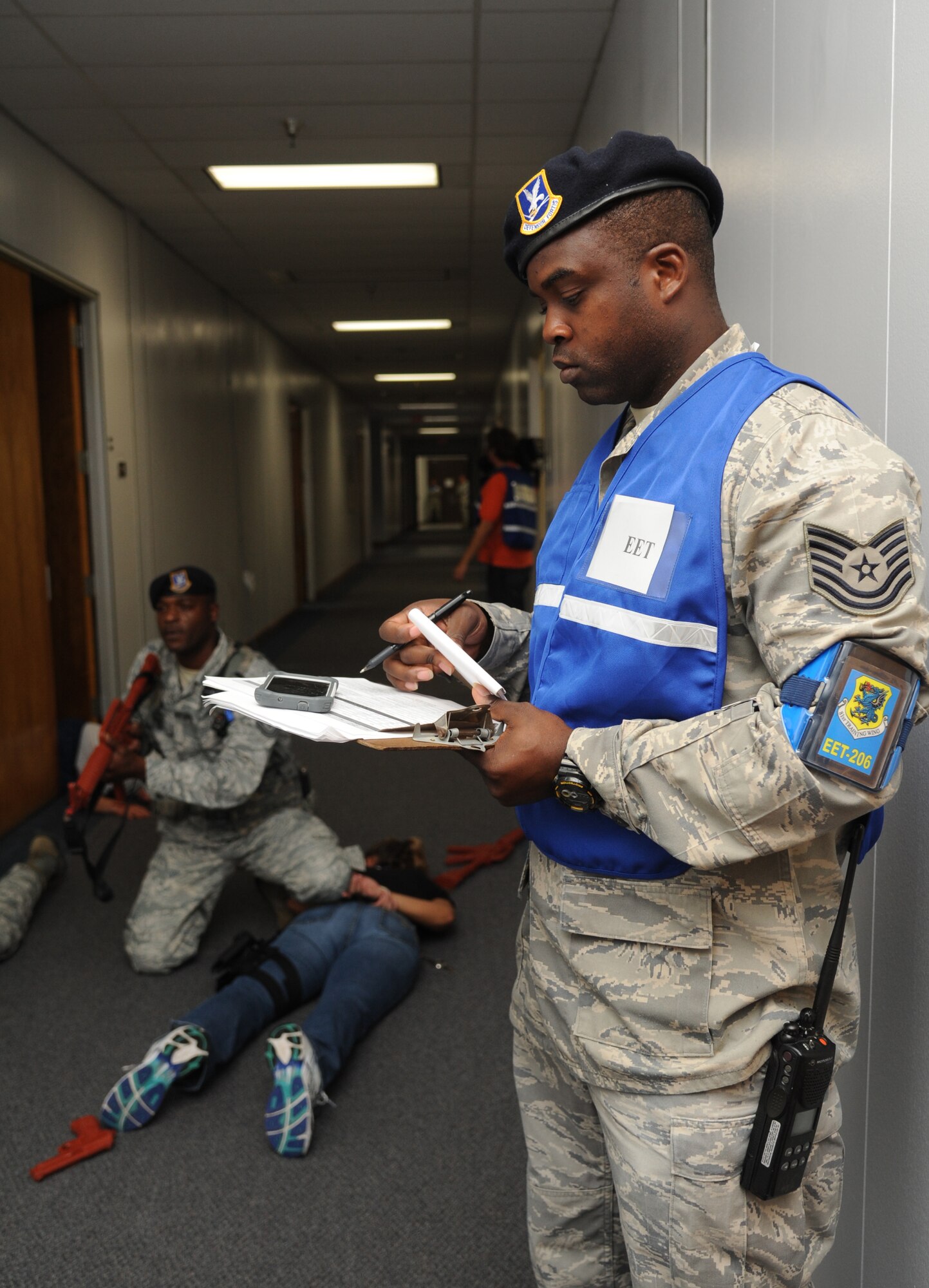 Tech. Sgt. Teddy Poole, 81st Security Forces Squadron, apprehends a portrayed gunman, as Tech. Sgt. Jason Gavin, 81st SFS exercise evaluation team member, takes notes during Keesler's active shooter exercise, June 12, 2013, at Garrard Hall, Keesler Air Force Base, Miss. During the two-day exercise, an Air Force couple simulated opening fire, killing three people and injuring 41.  The exercise tested the base's ability to respond to and recover from a mass casualty event.  (U.S. Air Force photo by Kemberly Groue)
