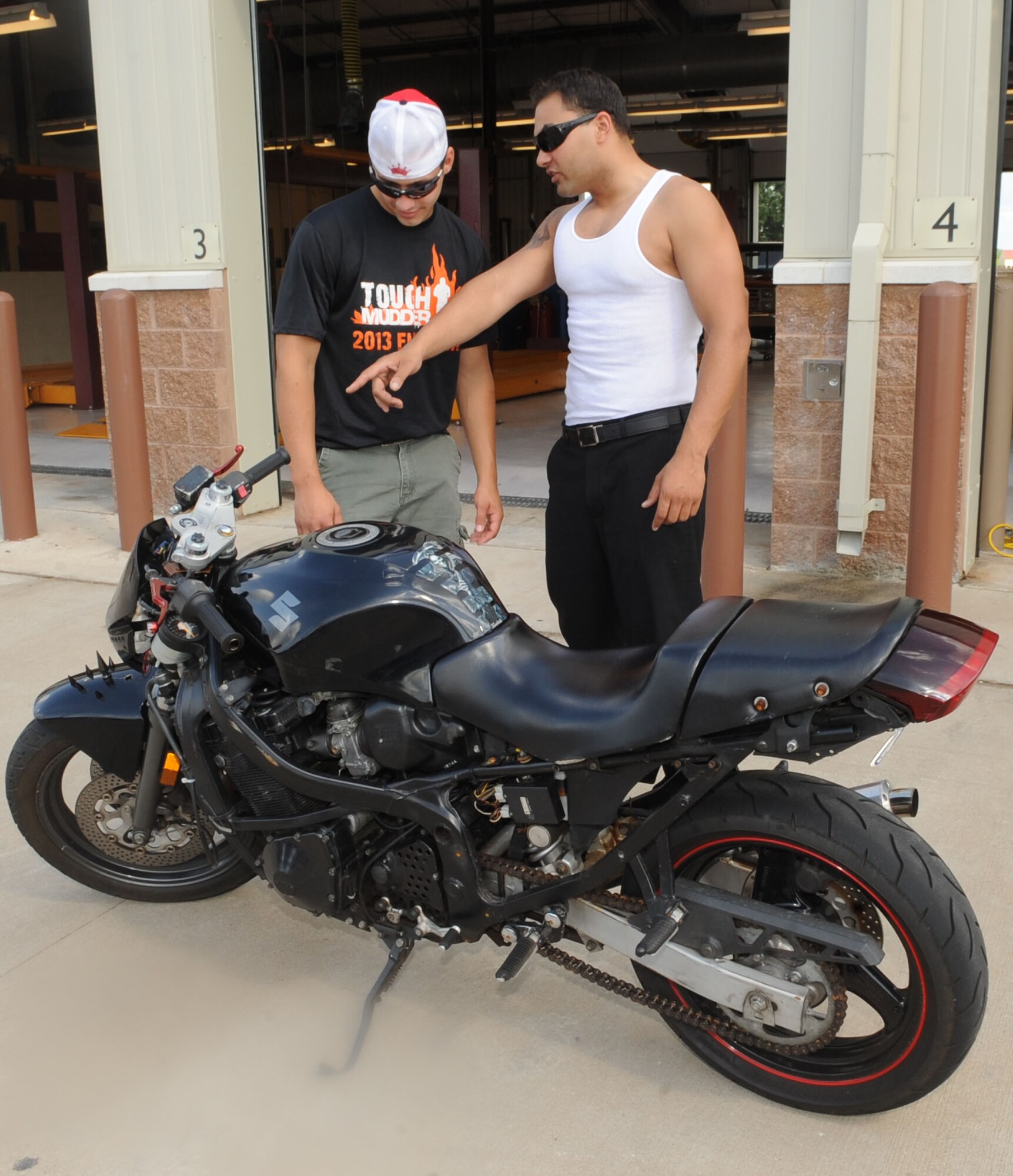 Airman 1st Class Jeremy Fazal, 2nd Maintenance Squadron, shows Airman 1st Class Cody Lechner, 2nd Aircraft Maintenance Squadron, his customized 1991 Suzuki Street Fighter during the Auto Hobby Car & Bike Meet on Barksdale Air Force Base, La., June 7, 2013. The meet gave auto and motorcycle enthusiasts a chance to gather and show case their vehicles. (U.S. Air Force photo/Senior Airman Kristin High)