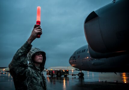 A 437th Aircraft Maintenance Squadron crew chief uses a marshaling glow stick to signal clearance of the left wing of a C-17 Globemaster III as it is towed into place to be chained down June 6, 2013, at Joint Base Charleston – Air Base, S.C. The C-17 was chained to the ground due to approaching tropical storm Andrea. (U.S. Air Force photo/ Senior Airman Dennis Sloan)