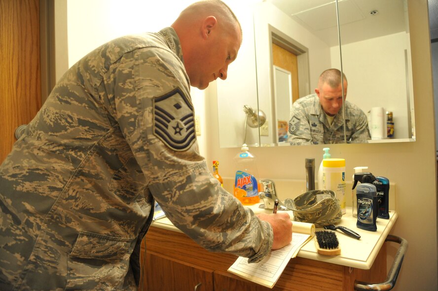 Master Sgt. Donald Gray, 509th Bomb Wing first sergeant, records discrepancies on an inspection checklist at Whiteman Air Force Base, Mo., June 3, 2013. First sergeants conduct regular dorm inspections to ensure living environments are being kept clean, sanitary and livable. (U.S. Air Force photo by Airman 1st Class Keenan Berry/Released)