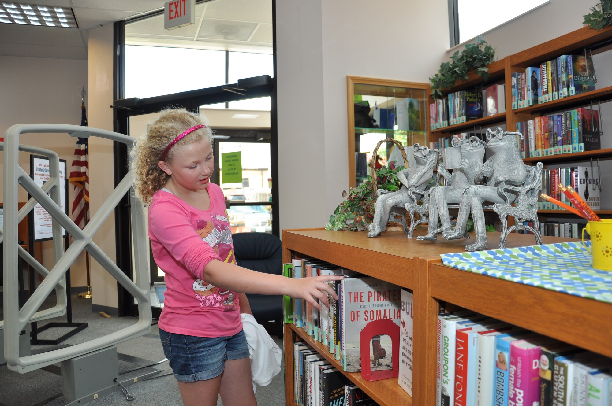 Kendra Kelly, 11, browses through the books at the Scott Library June 10 after signing up for the Summer Reading Program. The DoD’s theme this year is “Have book, will travel” and will consist of themed reading sessions and events from local performers. (U.S. Air Force photo/Airman 1st Class Josh Eikren)
