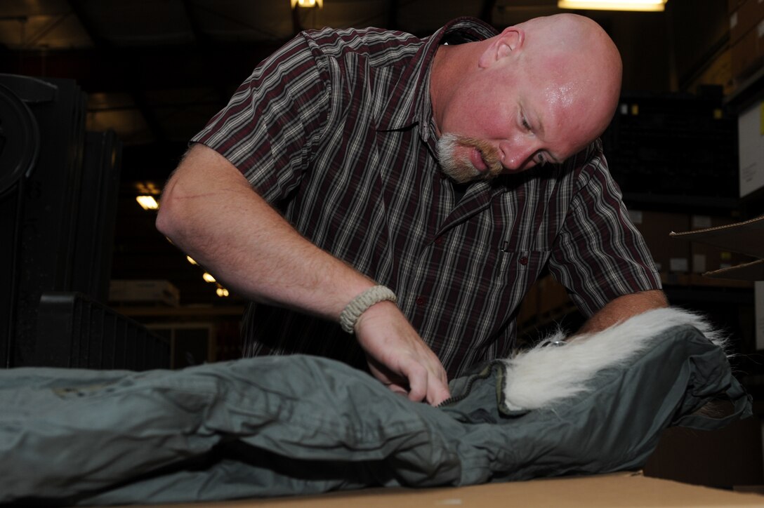 Jason DeCoster, 28th Civil Engineer Squadron material controls supply technician, inspects a winter parka during a routine inventory in the material controls warehouse on Ellsworth Air Force Base, S.D., June 6, 2013.  The warehouse contains various cold weather gear, specialty uniforms and deployment equipment for 28th CES Airmen with mission essential items. (U.S. Air Force photo by Senior Airman Kate Maurer/Released)