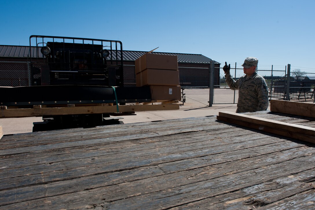 Staff Sgt. Gordon Williamson, 28th Civil Engineer Squadron heavy equipment technician, guides Christy Wolfe, 28th CES material controls supply technician, while loading parts at the Material Controls warehouse on Ellsworth Air Force Base, S.D., May 8, 2013. The parts are for street sweepers that heavy equipment technicians use throughout the year to help keep Ellsworth streets clean and free of safety hazards. (U.S. Air Force photo by Senior Airman Kate Maurer/Released)