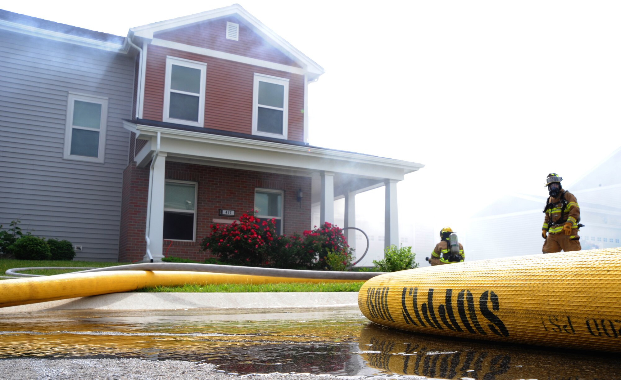 Firefighters from the 509th Civil Engineer Squadron practice entering a simulated burning house during an exercise at Whiteman Air Force Base, Mo., June 7, 2013. The fire services mission is to prevent fires; minimize injuries and loss of lives; protect property and the environment during periods of peace, war, military operations other than war; and provide humanitarian support operations for those charged in their care. (U.S. Air Force photo by Airman 1st Class Bryan Crane/Released)
