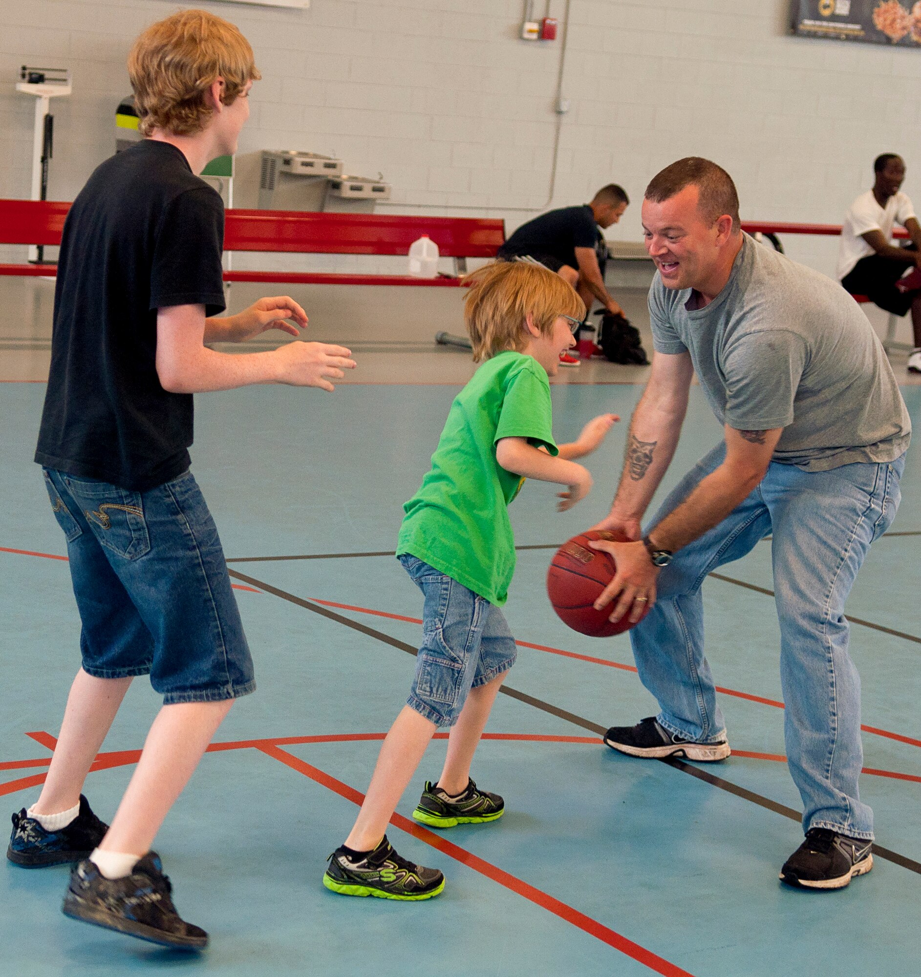 From left, Cassieus and Trystan Ducote play basketball with their father U.S. Army Staff Sgt. Matthew Ducote, 221st Military Police Detachment patrol platoon sergeant, at Anderson Field House on Fort Eustis, Va., June 10. Ducote is a father of four who believes it’s important to teach his children military values.  (U.S. Air Force photo by Austin Harvill/Released) 