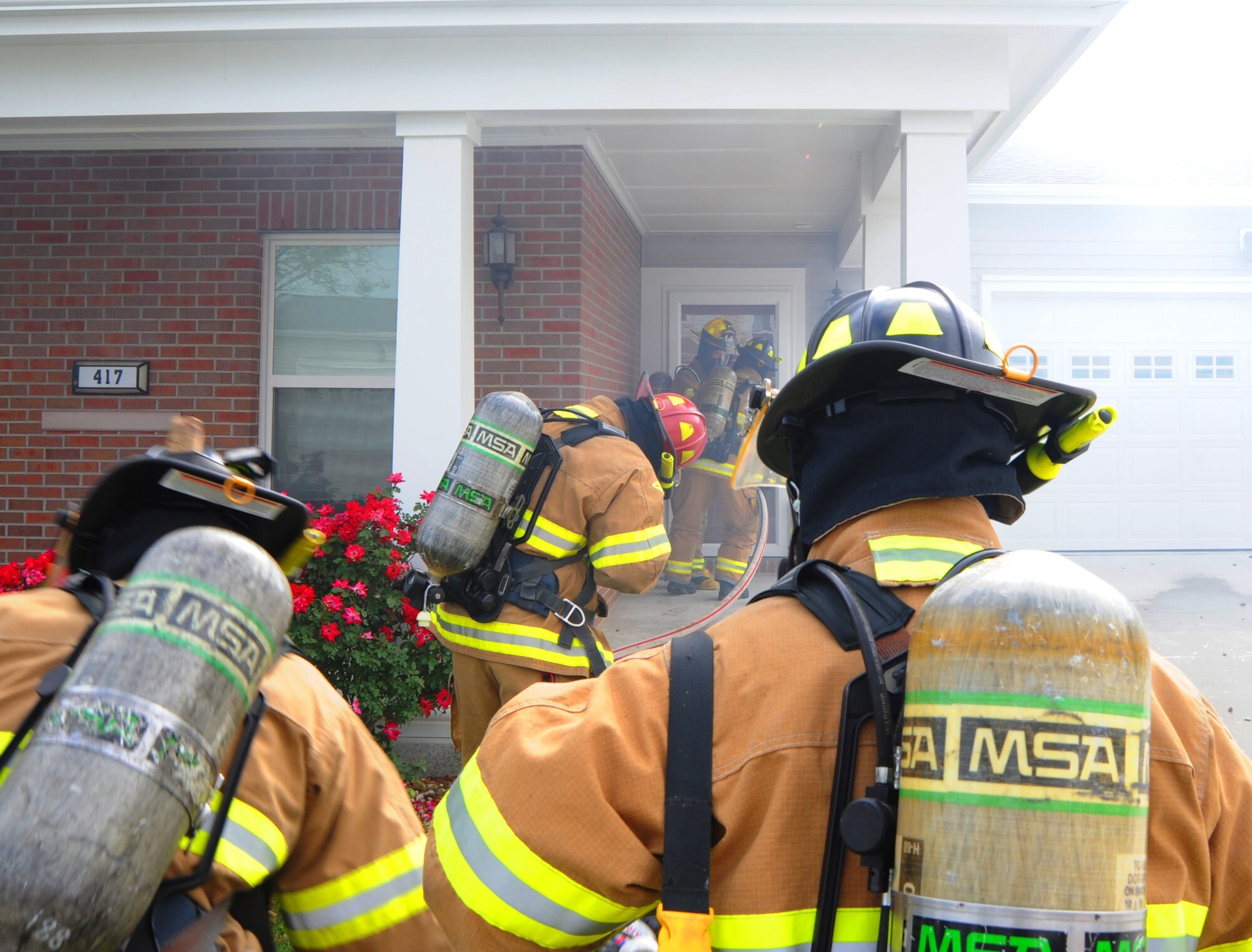 Firefighters from the 509th Civil Engineer Squadron prepare to enter a simulated burning house at Whiteman Air Force Base, Mo., June 7, 2013. The fire department is required to conduct upgrade training and exercises throughout the year to keep their skills up-to-date and mission-ready. (U.S. Air Force photo by Airman 1st Class Bryan Crane/Released)