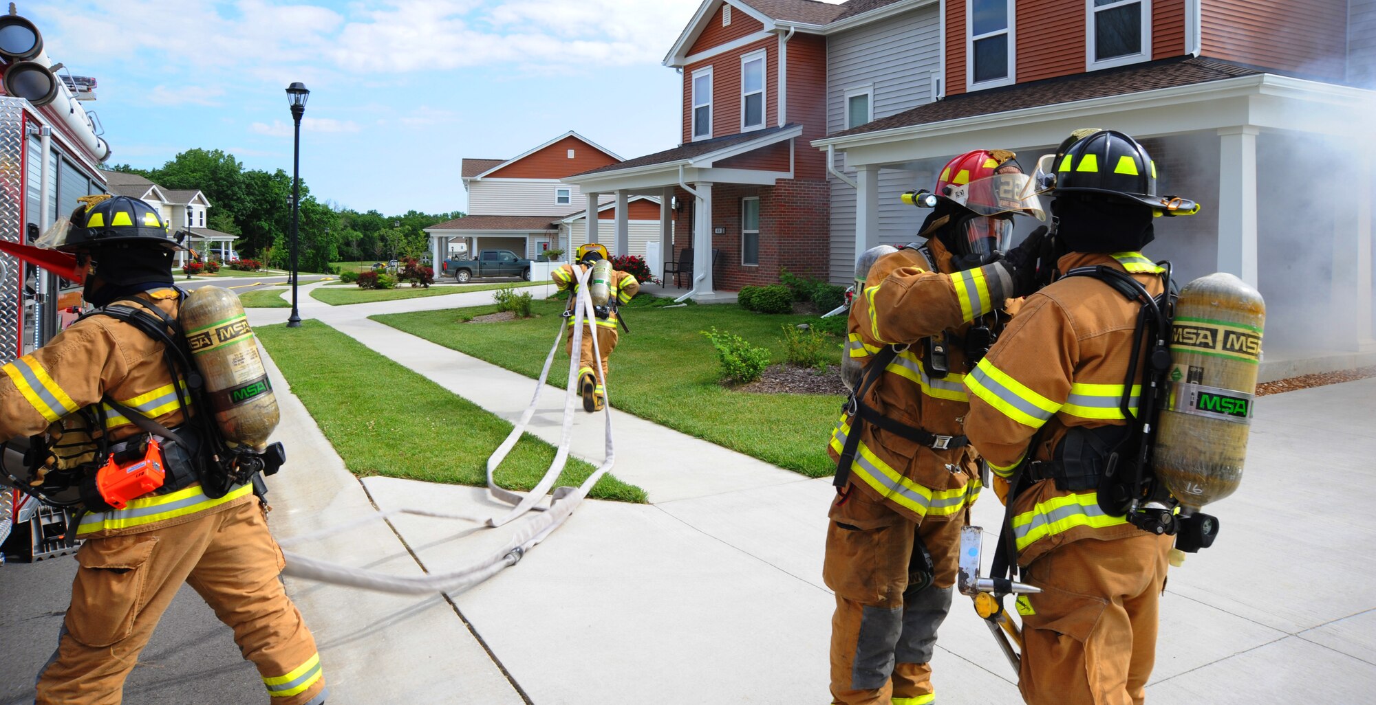 Firefighters from the 509th Civil Engineer Squadron rush to the scene of a mock fire at Whiteman Air Force Base, Mo., June 7, 2013. The fire fighters had to show how well they could work together to rescue a mock victim from a burning house. (U.S. Air Force photo by Airman 1st Class Bryan Crane/Released)