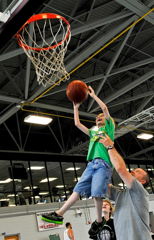 U.S. Army Staff Sgt. Matthew Ducote, 221st Military Police Detachment patrol platoon sergeant, lifts his son Trystan into the air to score during a basketball game at Anderson Field House on Fort Eustis, Va., June 10. Ducote spends his off-duty time playing games and fishing with his children and family. (U.S. Air Force photo by Staff Sgt. Wesley Farnsworth/Released)