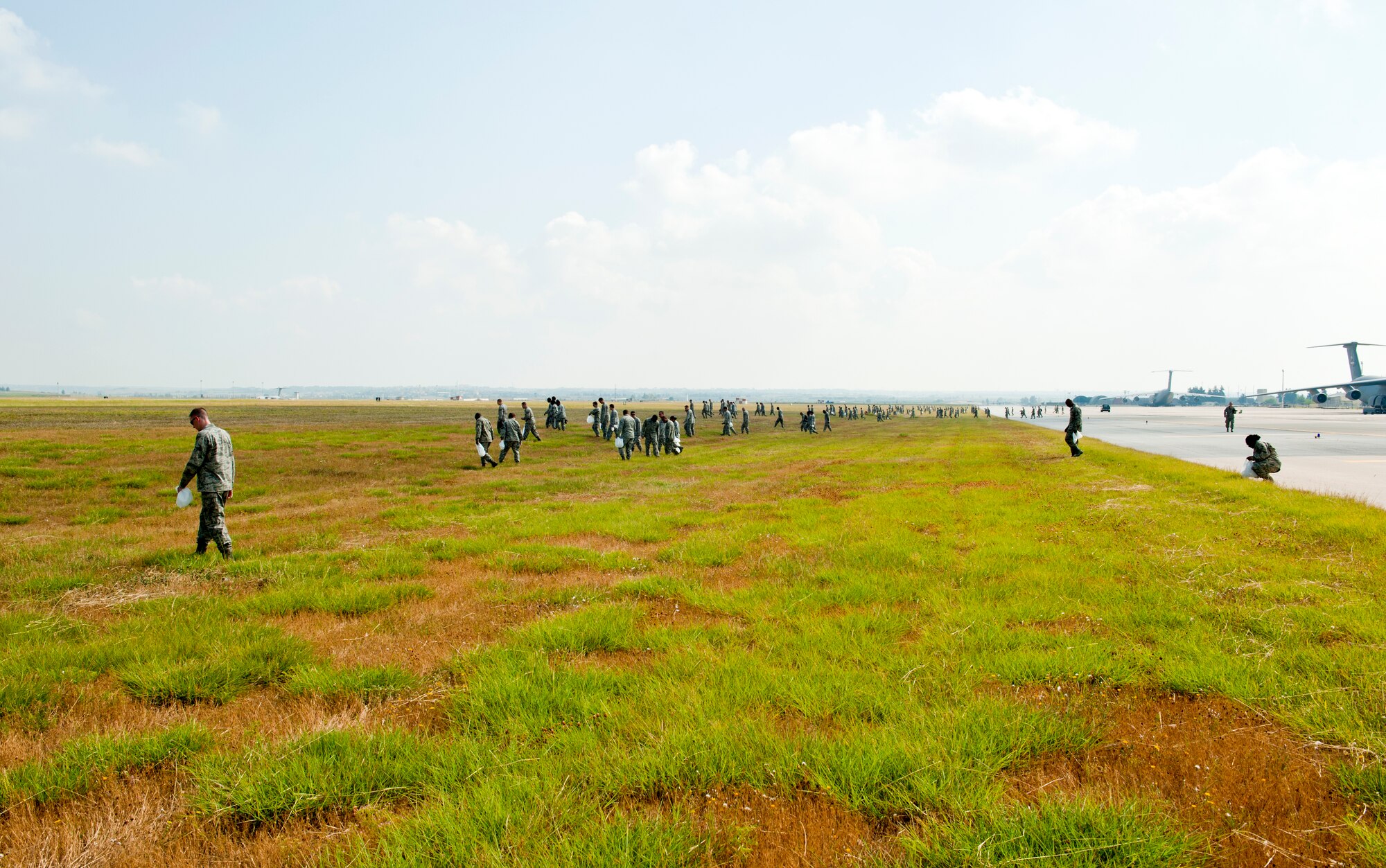 Airmen from the 39th Air Base wing comb the grass for foreign object debris June 12, 2013, at Incirlik Air Base, Turkey. The 39th ABW and Turkish air force 10th Tanker Base Command performed a combined FOD walk to search for trash and debris that could damage aircraft. (U.S. Air Force photo by Senior Airman Daniel Phelps/Released)