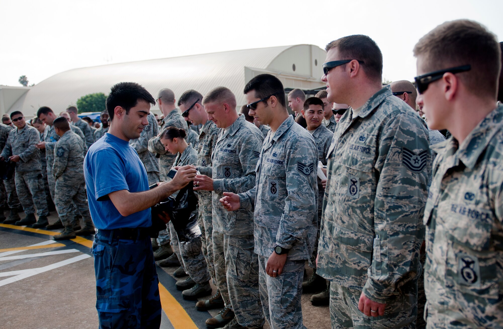 A Turkish airman passes out trash bags to Airmen from the 39th Air Base Wing for a combined foreign object debris walk with the Turkish air force 10th Tanker Command and 39th ABW on the flightline June 12, 2013, at Incirlik Air Base, Turkey. Both units removed trash and debris that could potentially harm aircraft engines. (U.S. Air Force photo by Senior Airman Daniel Phelps/Released)