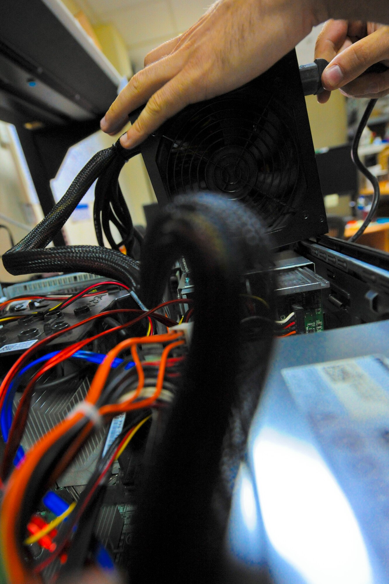 U.S. Air Force Airman 1st Class Braden Hoglan; 380th Expeditionary Communication Squadron small computer repair technician; uses an external power supply to troubleshoot a computer unit at an undisclosed location in Southwest Asia June 11; 2013. The power supply allows Hoglan to distinguish between a power issue or other internal parts issue.; Hoglan is native to Amesbury; Mass.; and is deployed from Ramstein Air Base; Germany. (U.S. Air Force photo by Staff Sgt. Joshua J. Garcia)