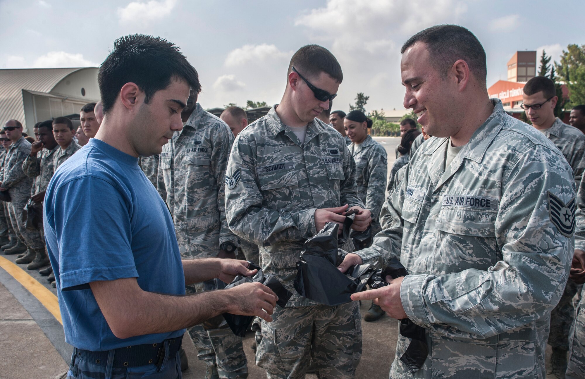 Staff Sgt. Dustin Hayes, right, 39th Communications Squadron, receives a plastic bag from a member of the Turkish air force during a foreign-object-debris walk June 12, 2013, at Incirlik Air Base, Turkey. During the FOD walk, U.S. and Turkish airmen from the 39th Air Base Wing and the 10th Tanker Base Command removed trash and debris from the flightline. (U.S. Air Force photo by Senior Airman Anthony Sanchelli/Released)