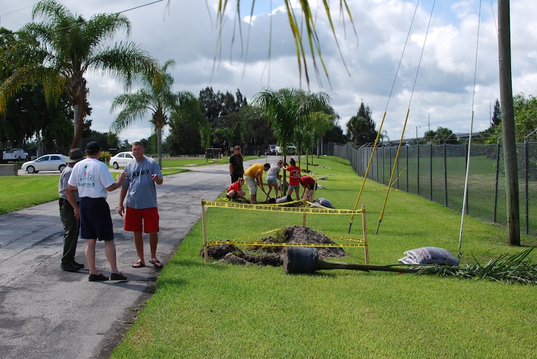 Steve Dunham, chief of the South Florida Operations Office in Clewiston (in white shirt) and park ranger Richard Bailey speak with army instructor Sergeant First Class Brian Lamberton as JROTC volunteers plant Royal Palms along the entrance to the Port Mayaca Lock & Dam. 