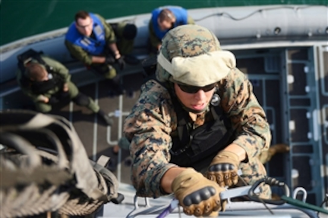 Marine Corps Lance Cpl. Darren Clay uses a Jacob's ladder to board the littoral combat ship USS Freedom during a joint visit, board, search and seizure exercise in Singapore, June 11, 2013. The Freedom is in Singapore on an overseas deployment.