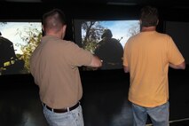 Brendan Klapak (left), Office of the Counsel, and Dave Keeler, Combat Support Systems, keep their weapons ready during a May training exercise at Camp Upshur’s Indoor Simulated Marksmanship Trainer. 
