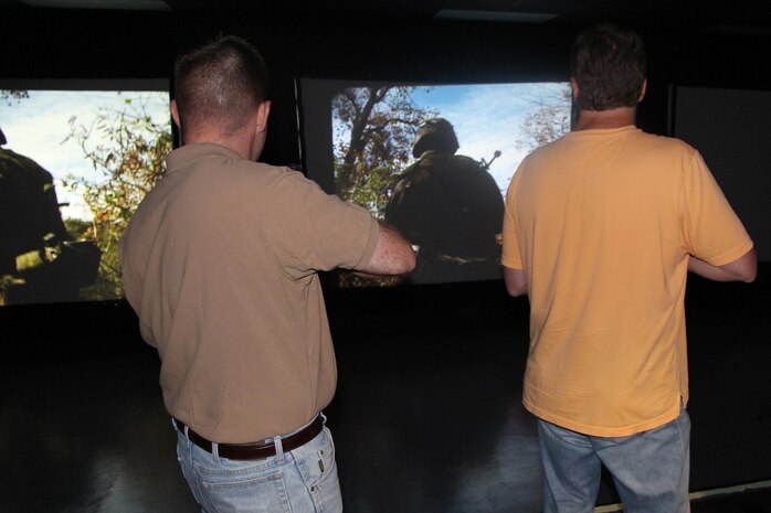 Brendan Klapak (left), Office of the Counsel, and Dave Keeler, Combat Support Systems, keep their weapons ready during a May training exercise at Camp Upshur’s Indoor Simulated Marksmanship Trainer. 