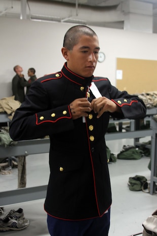 A recruit with Company K, 3rd Recruit Training Battalion, buttons his blue dress coat during a uniform fitting aboard Marine Corps Recruit Depot San Diego June 7.  